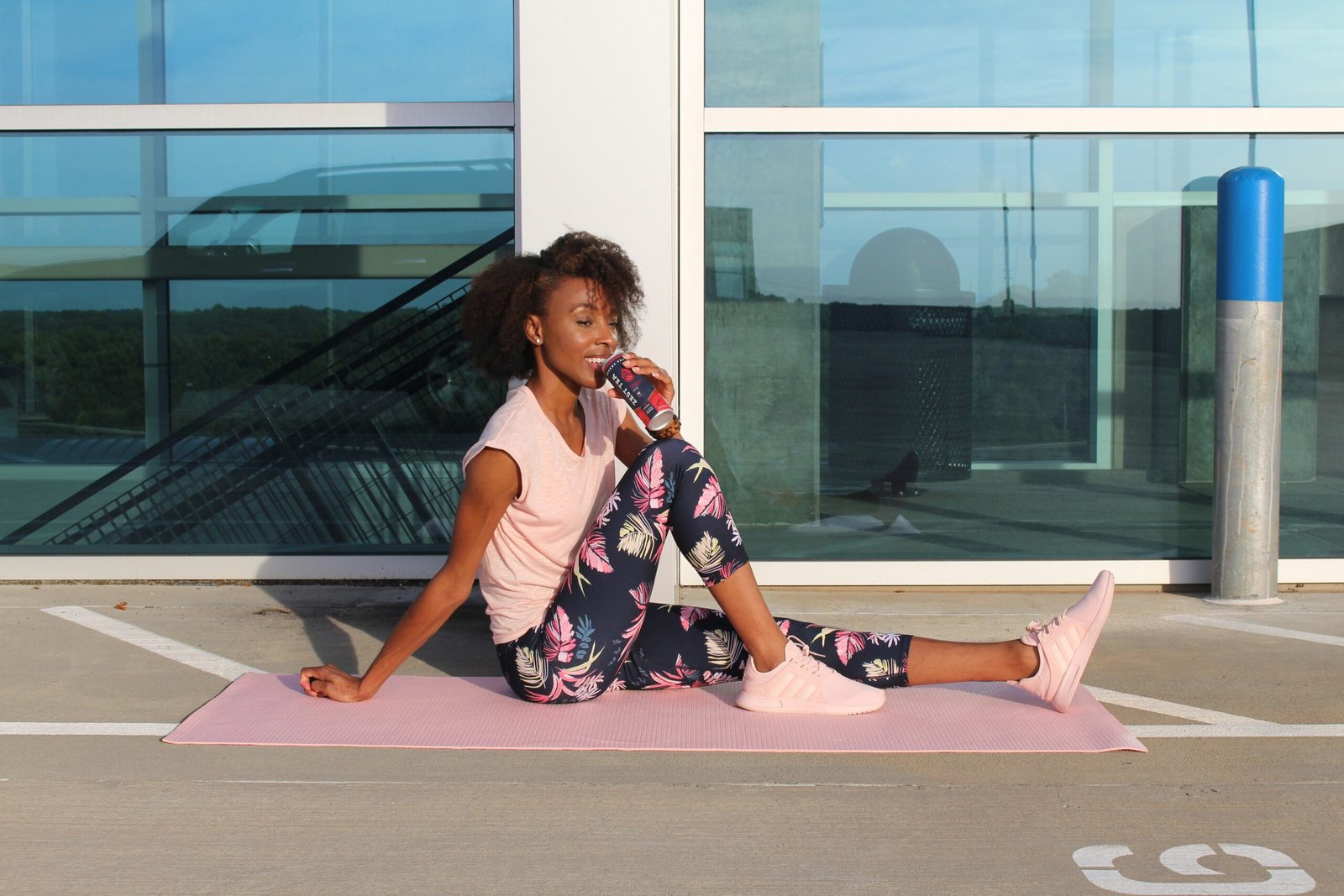 woman in white tank top and pink floral skirt sitting on floor